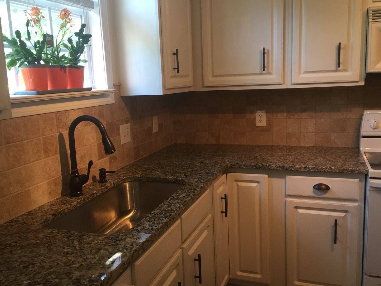 A kitchen with granite counter tops and white cabinets