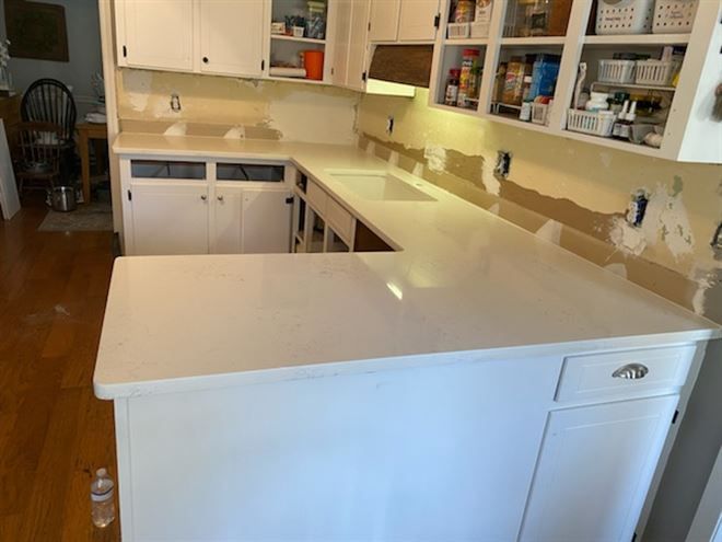 A kitchen with white cabinets and white counter tops is being remodeled.