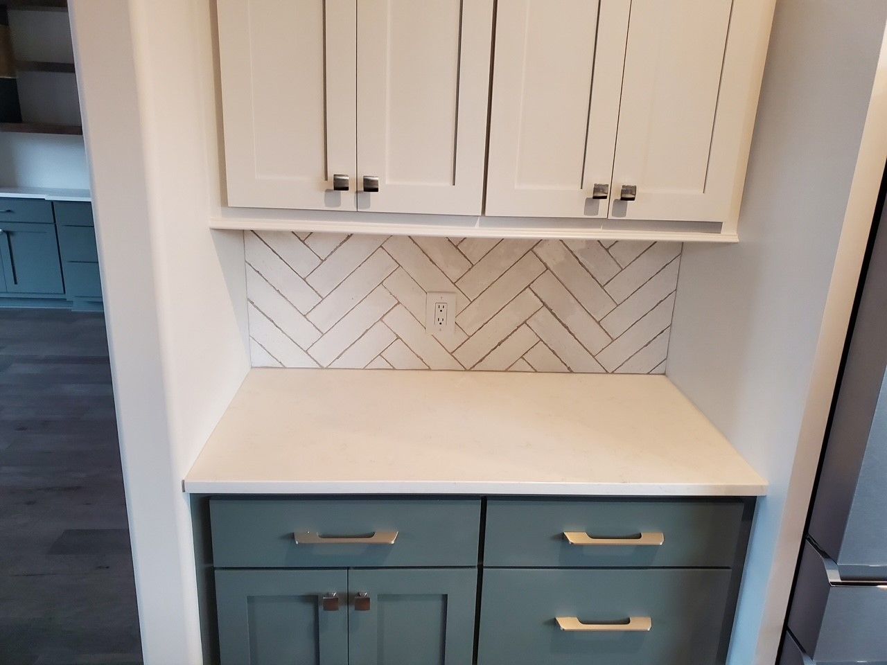 A kitchen with white cabinets and blue drawers and a white counter top.