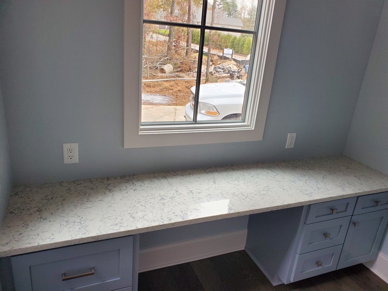 A long desk with drawers and a window in a room.