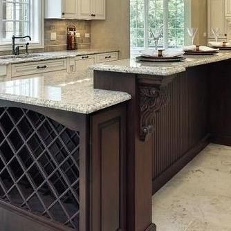 A kitchen with granite counter tops and a wine rack on the island.