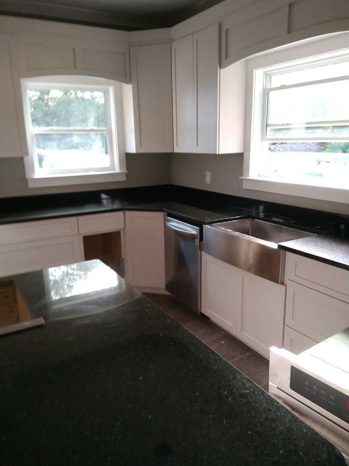 A kitchen with white cabinets and black counter tops