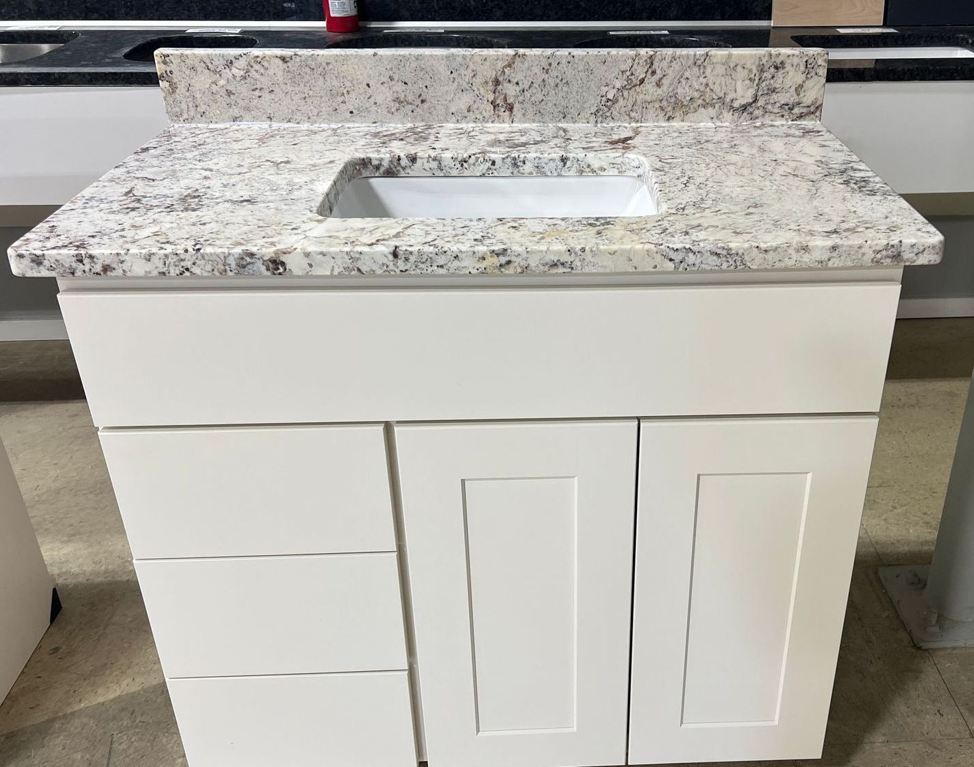 A white vanity with a granite counter top and sink