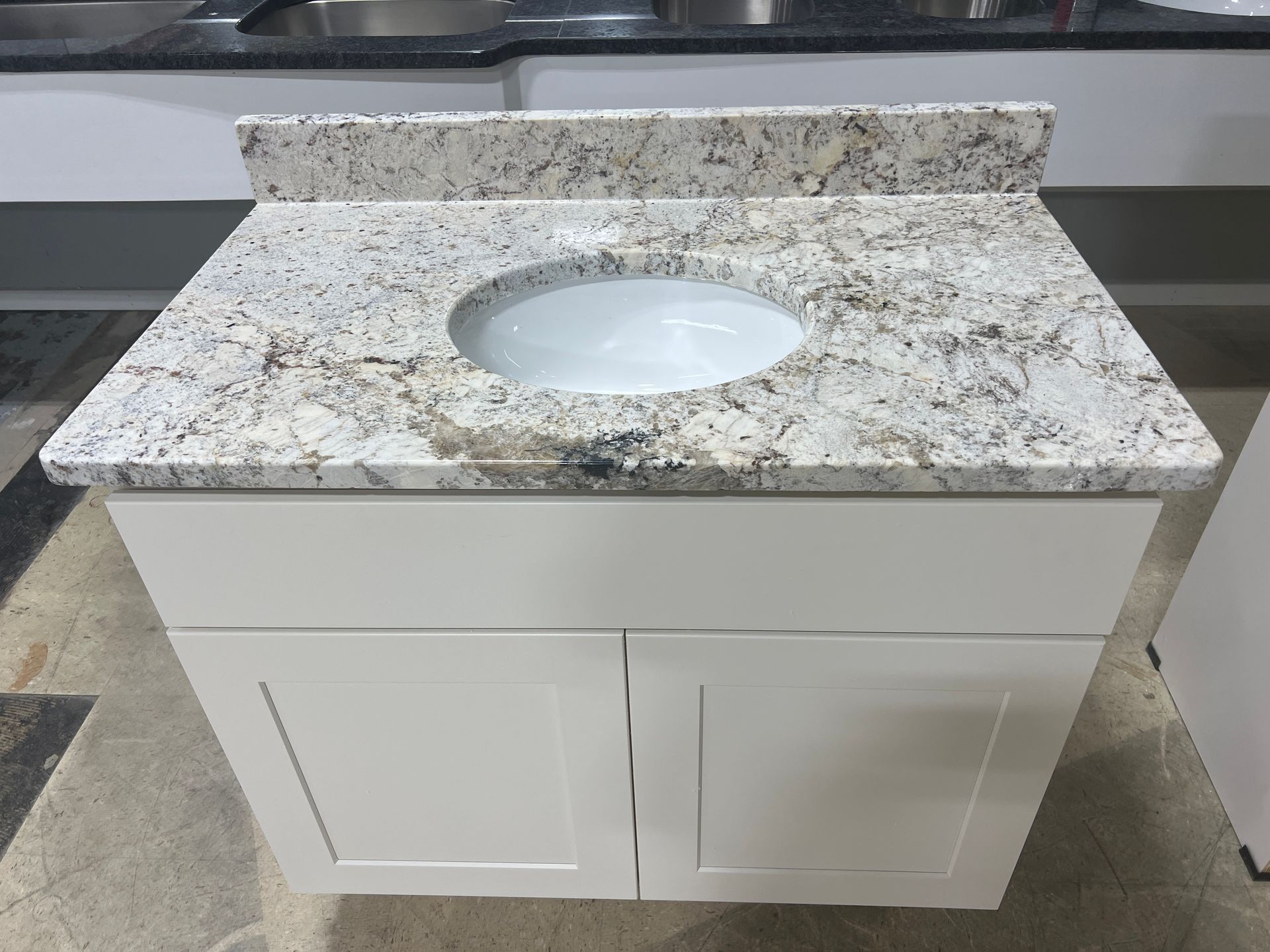 A bathroom vanity with a granite counter top and a sink.