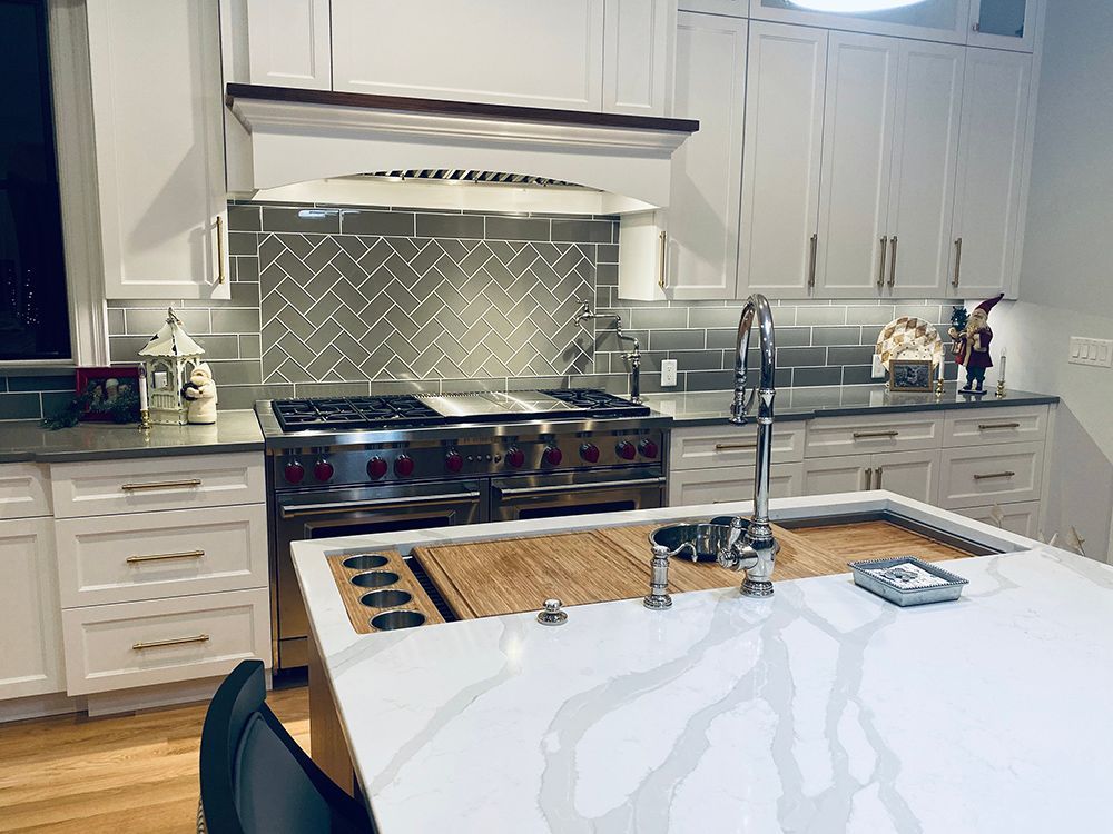 A kitchen with white cabinets , stainless steel appliances , and a large island.