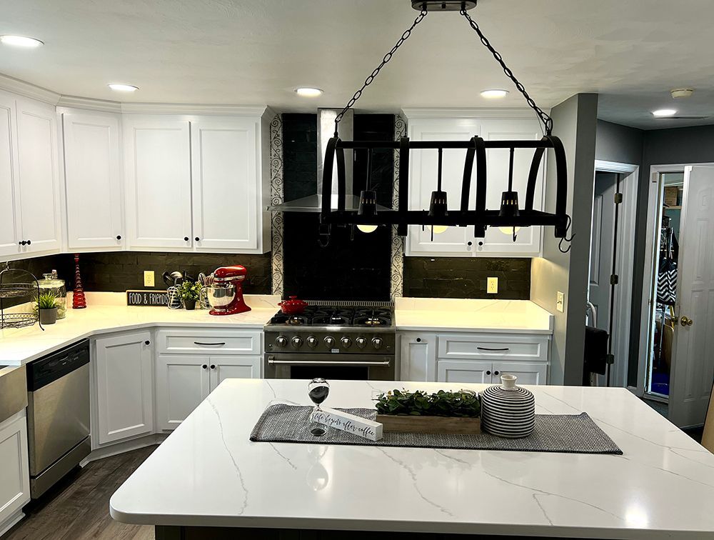 A kitchen with white cabinets , stainless steel appliances , and a large island.