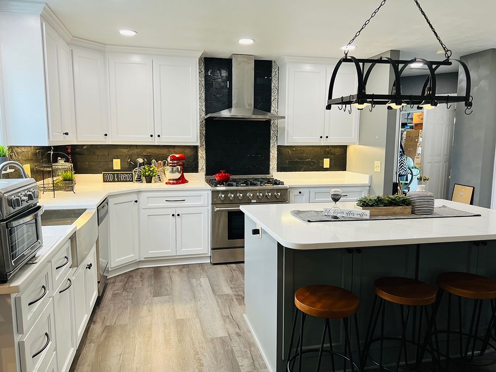 A kitchen with white cabinets , stainless steel appliances , and a large island.