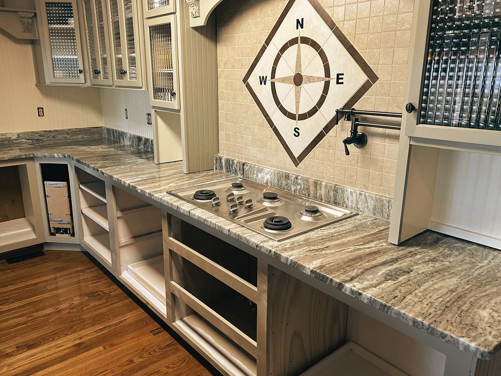 A kitchen with granite counter tops and a compass on the wall