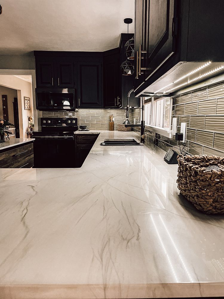 A kitchen with black cabinets and a white counter top.