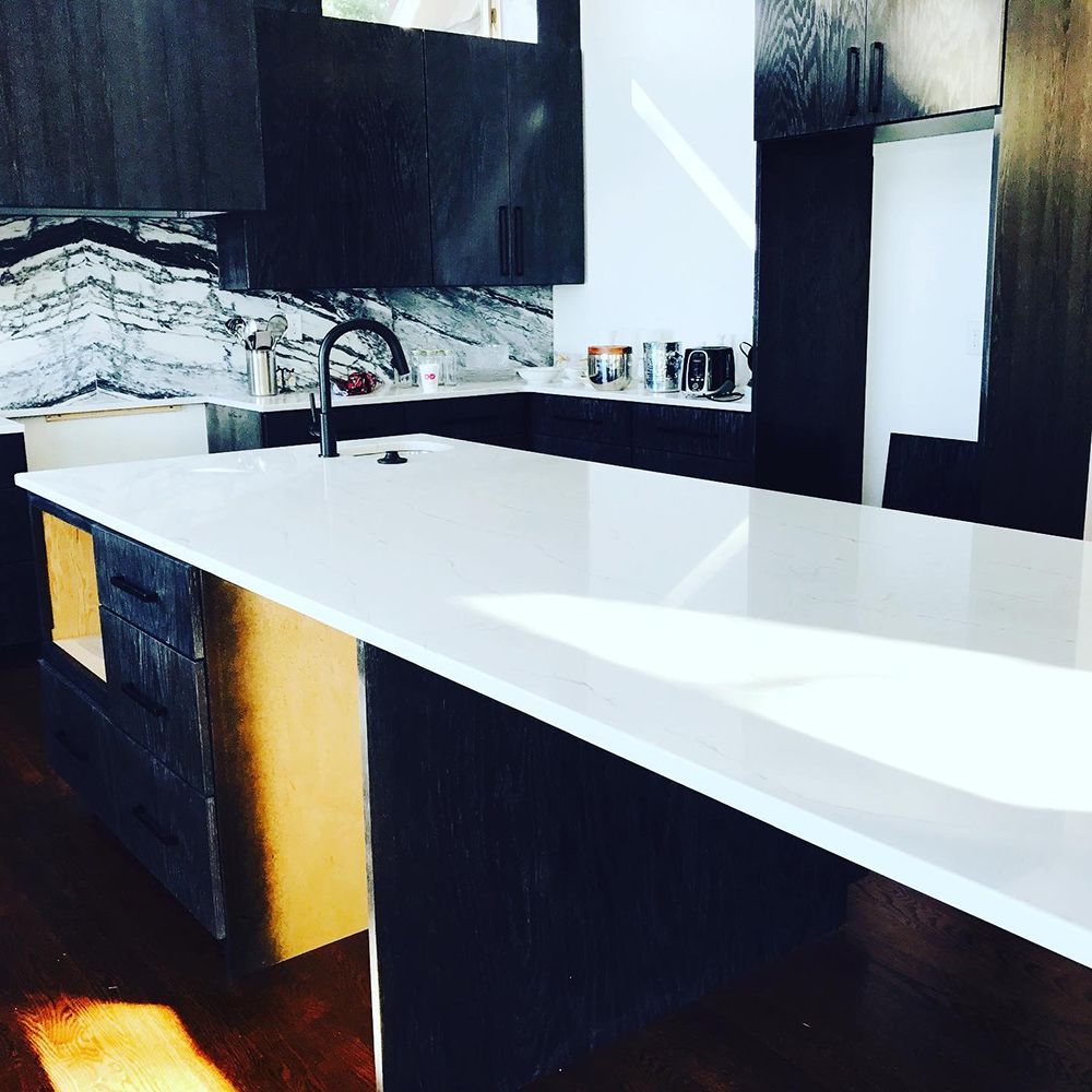A kitchen with black cabinets and white counter tops