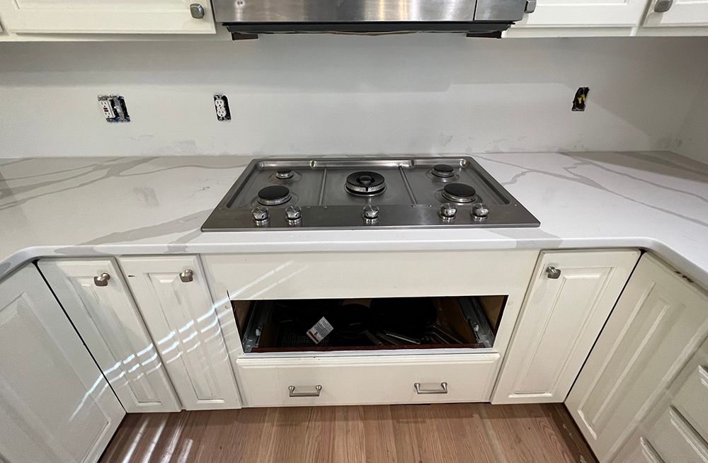 A kitchen with white cabinets and a stove top oven.