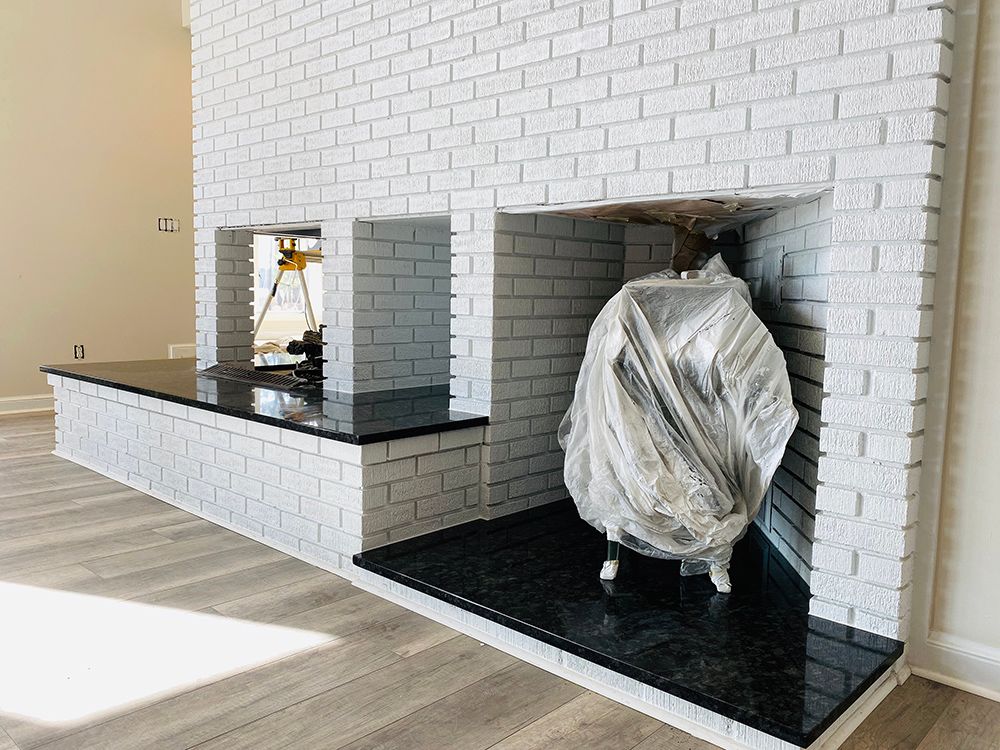 A white brick fireplace with a black granite hearth in a living room.
