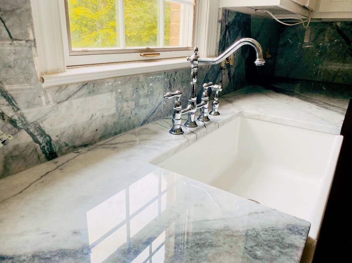 A kitchen sink with a faucet and a window in the background.