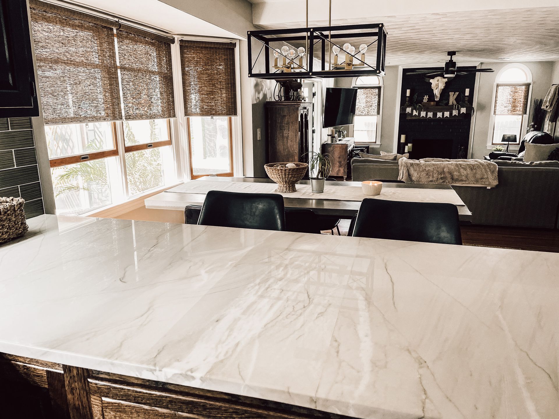 A kitchen with a marble counter top and a large window.