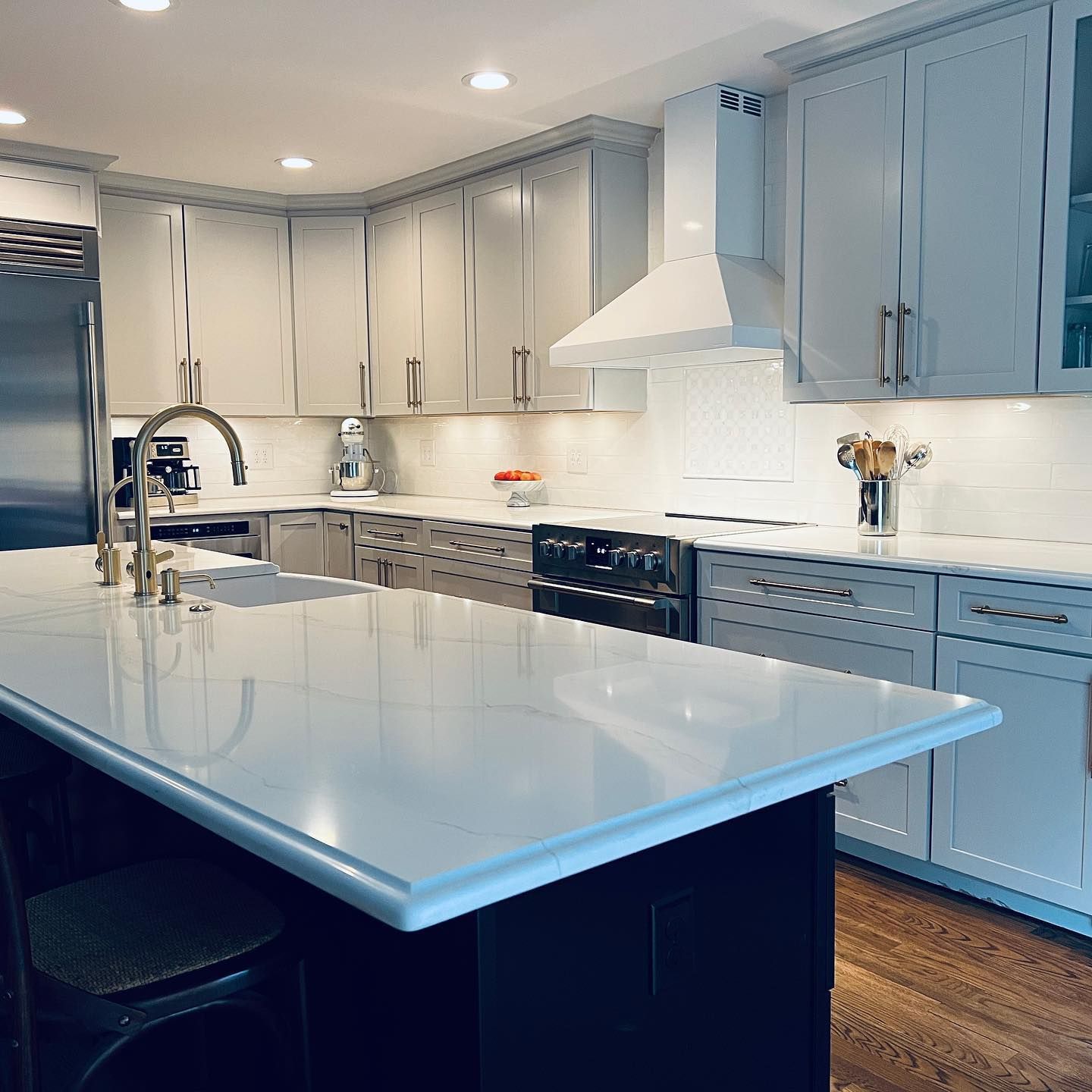 A kitchen with white cabinets , stainless steel appliances and a large island.