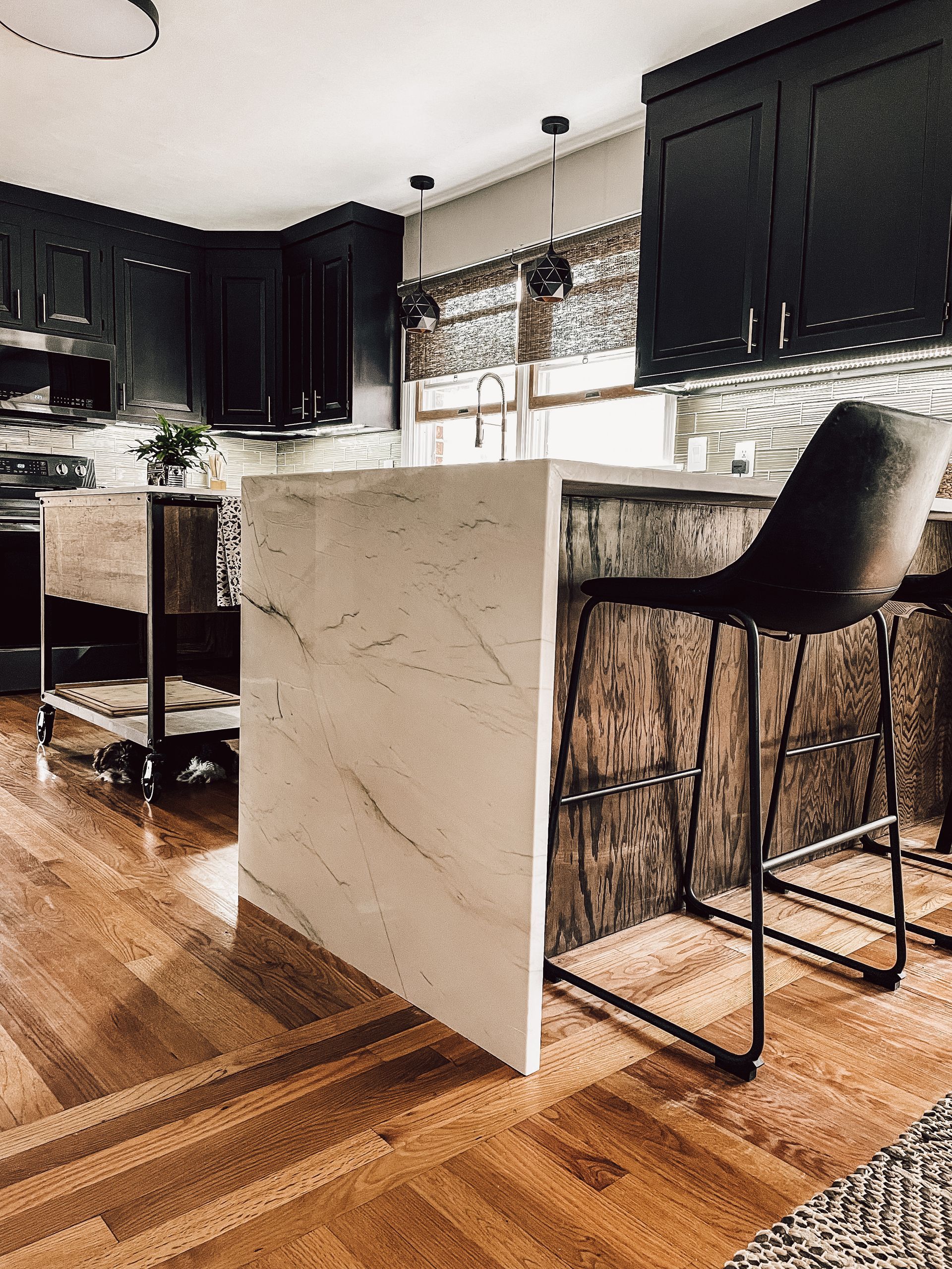 A kitchen with a large island and two bar stools.