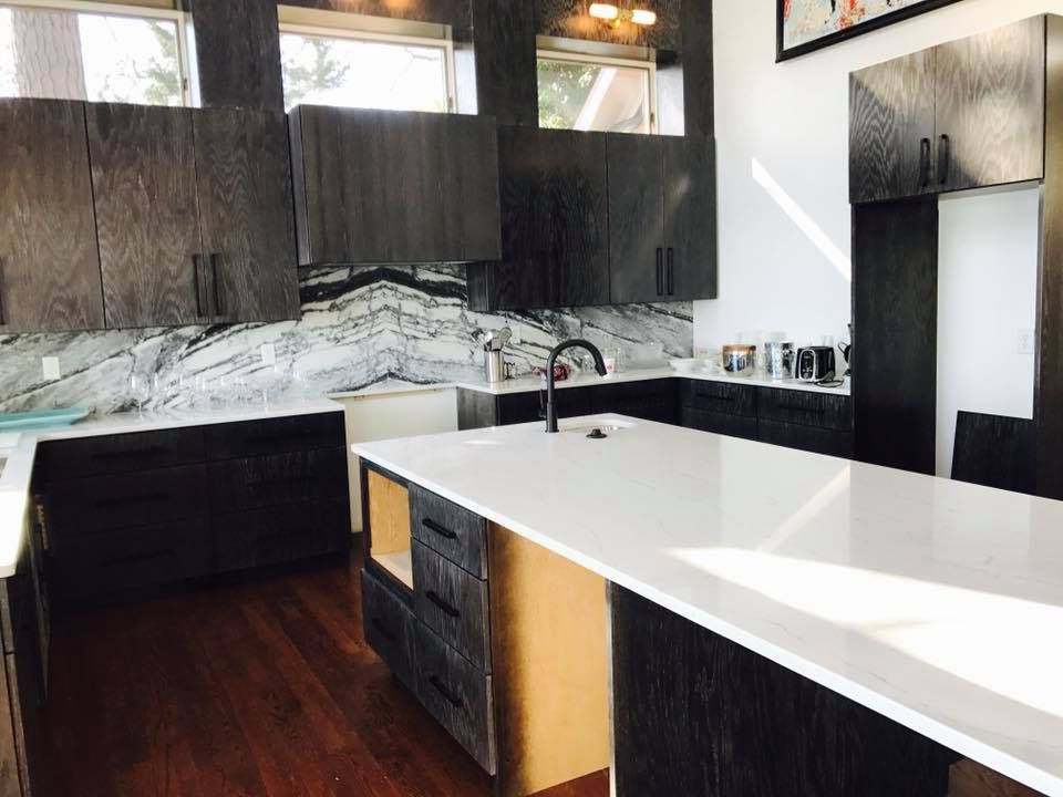 A kitchen with black cabinets and white counter tops