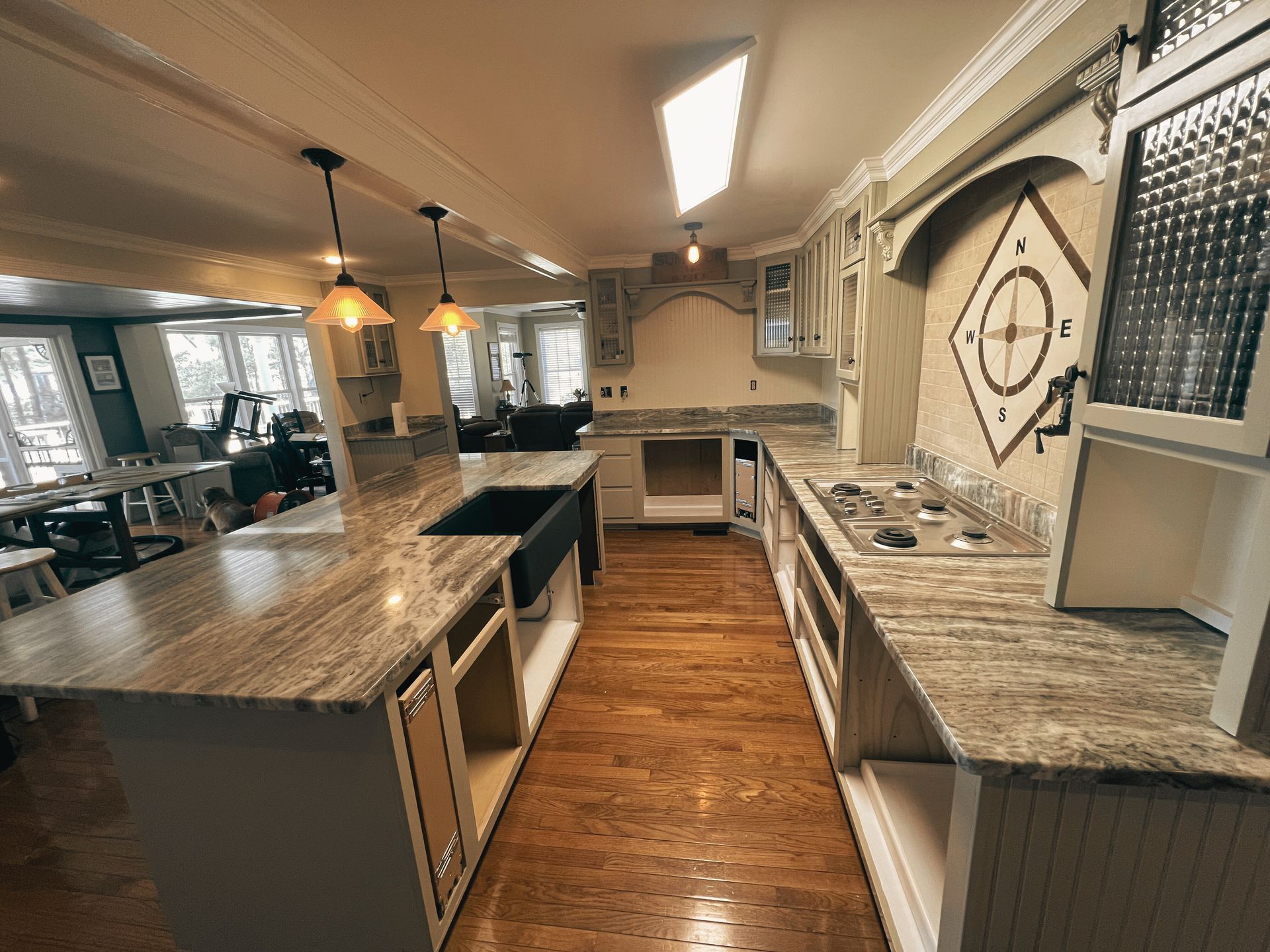 A long kitchen with granite counter tops and wooden floors.