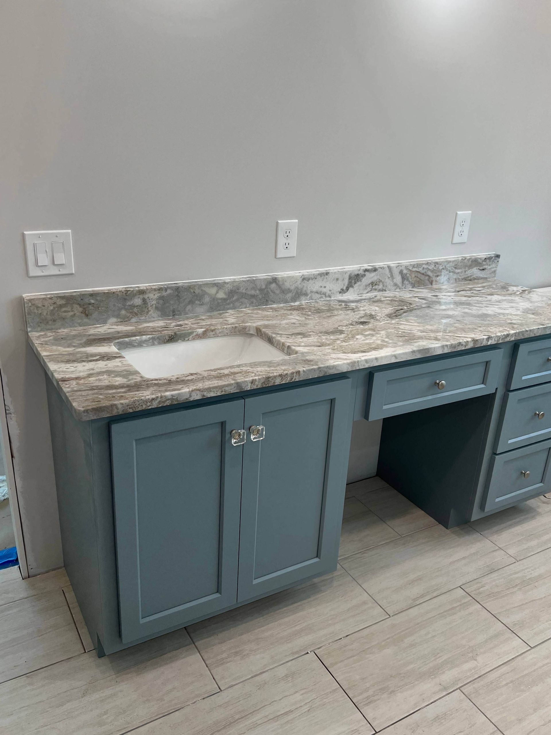 A bathroom with a sink , cabinets , and granite counter tops.