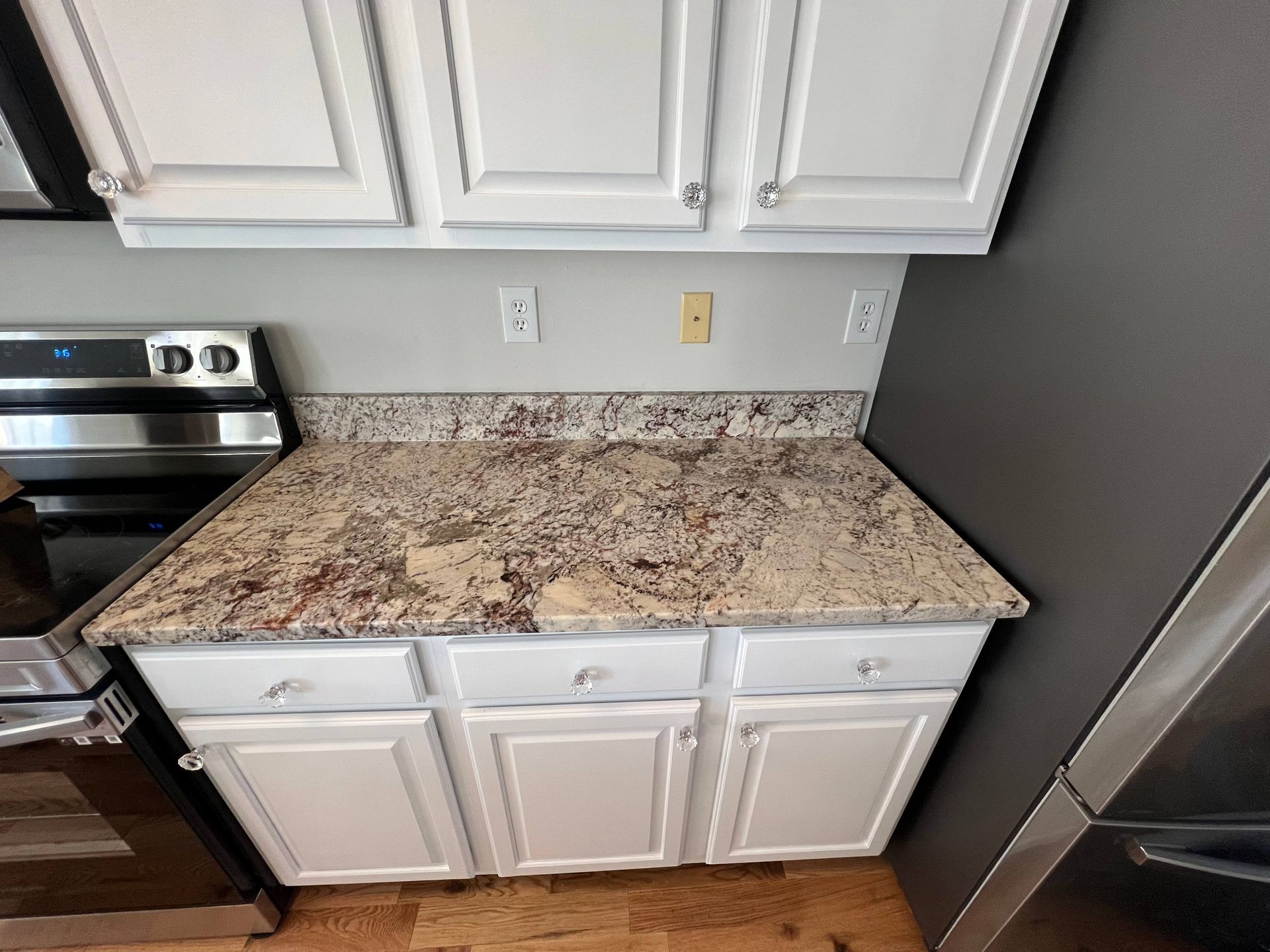 A kitchen with granite counter tops and white cabinets
