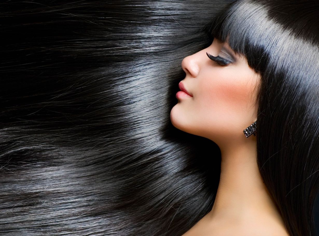Woman with glossy black hair, bangs, and side profile; eyes closed, blush.