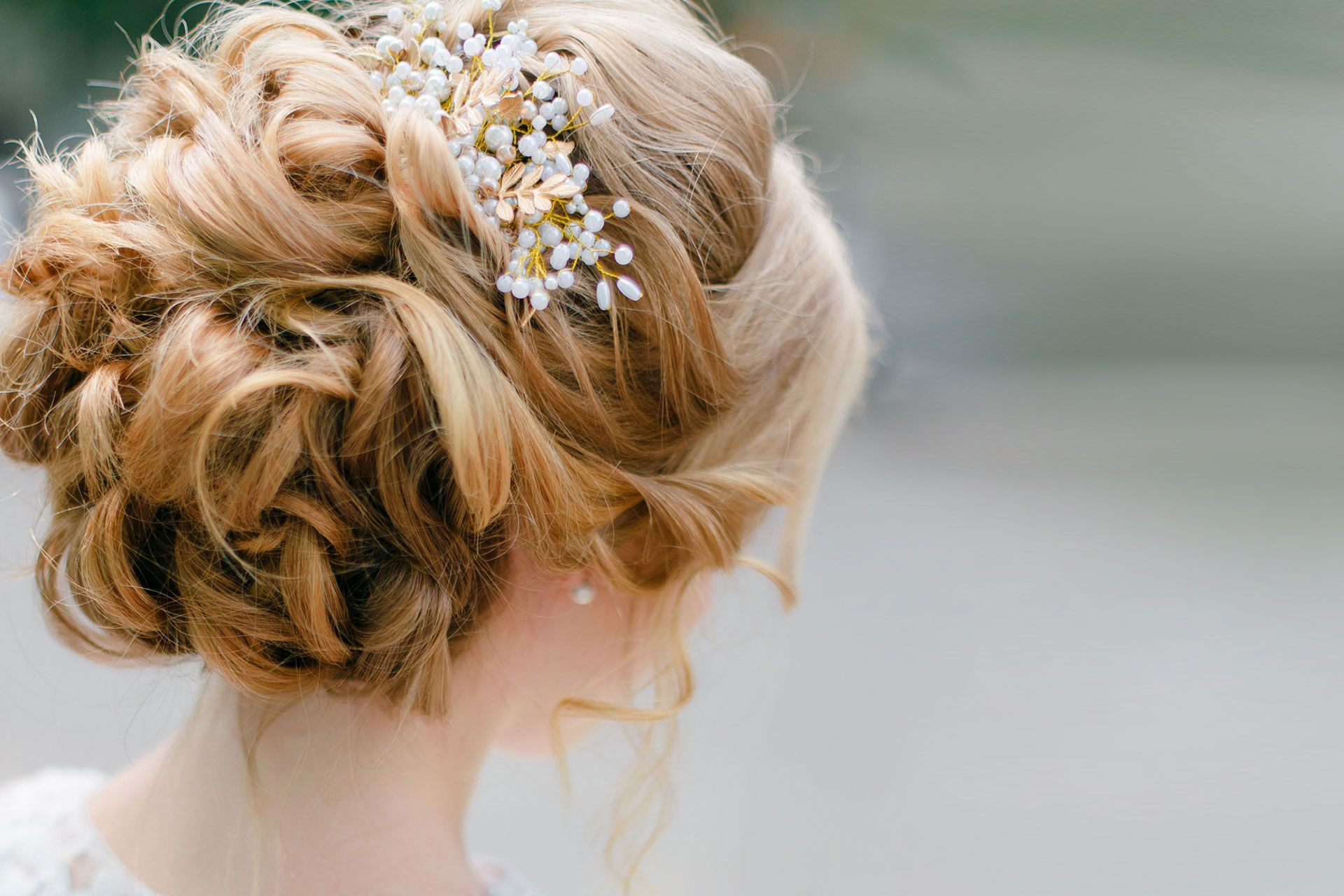 Woman with blonde updo hairstyle adorned with small white flowers.