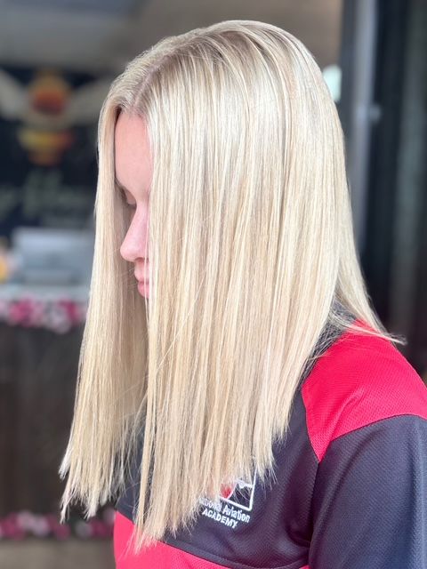 Wavy shoulder-length brown hair with blonde highlights, viewed from the back in a salon chair.
