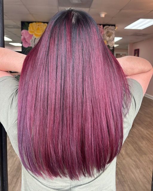 Long straight hair dyed magenta and pink, shown from the back in a salon setting.