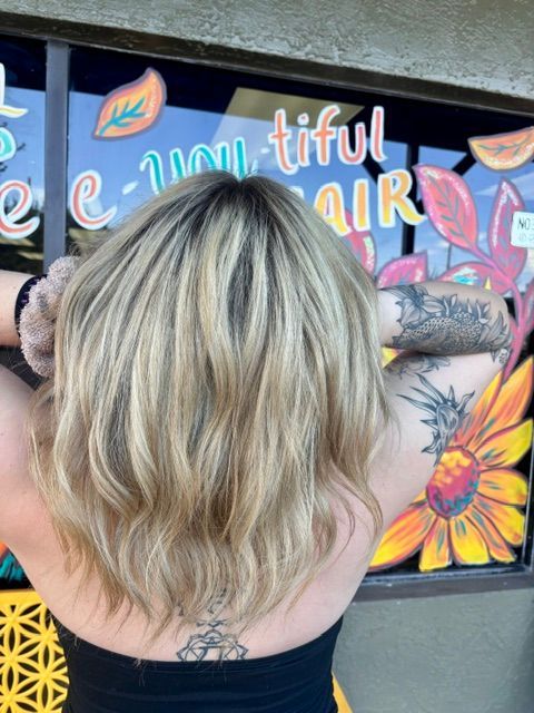 Person with blonde hair showing a back tattoo in front of a colorful mural.