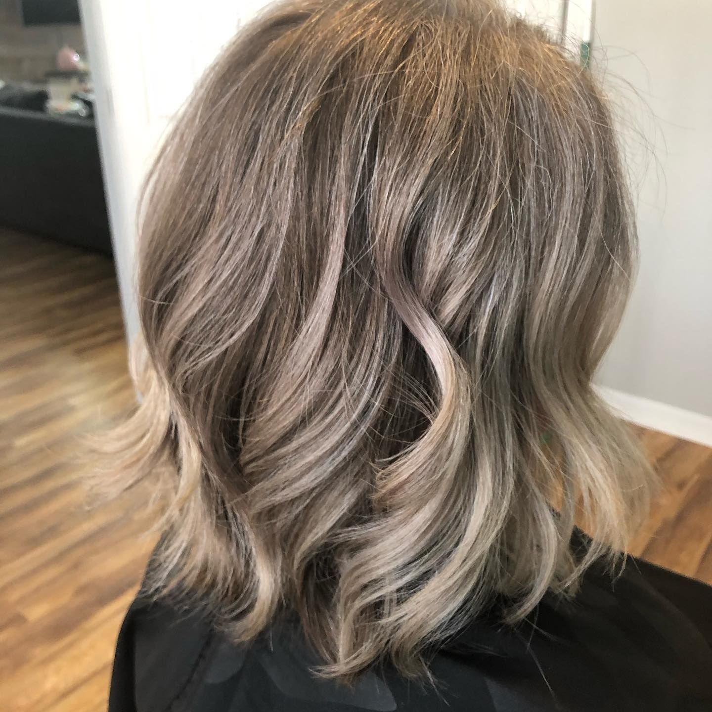 Woman with wavy, ash-blonde bob haircut, viewed from the back.