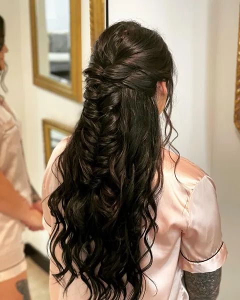 Woman with long dark hair in a half-up fishtail braid, wearing a pink satin robe.