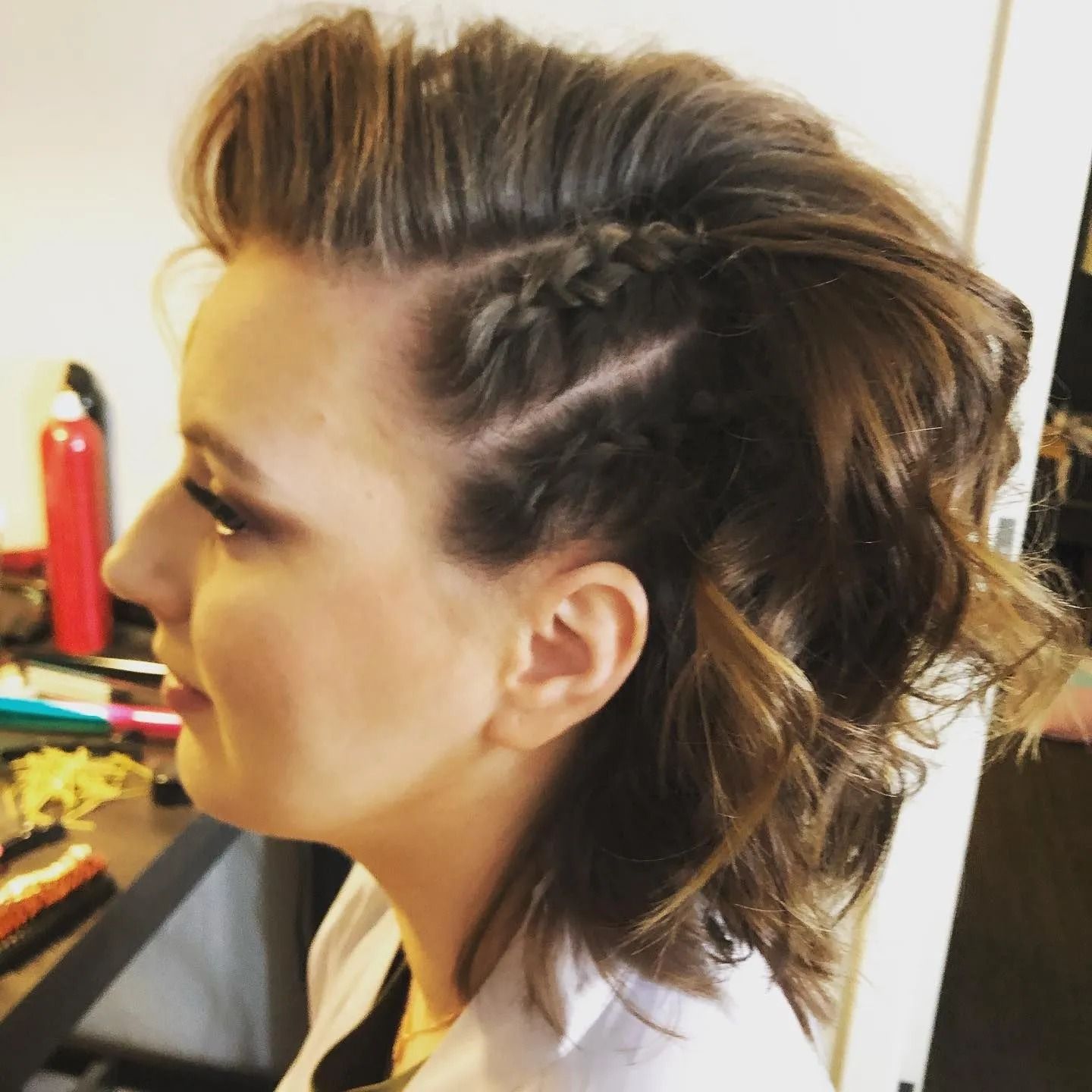 Woman with dark wavy hair, side-braid hairstyle, side profile view.