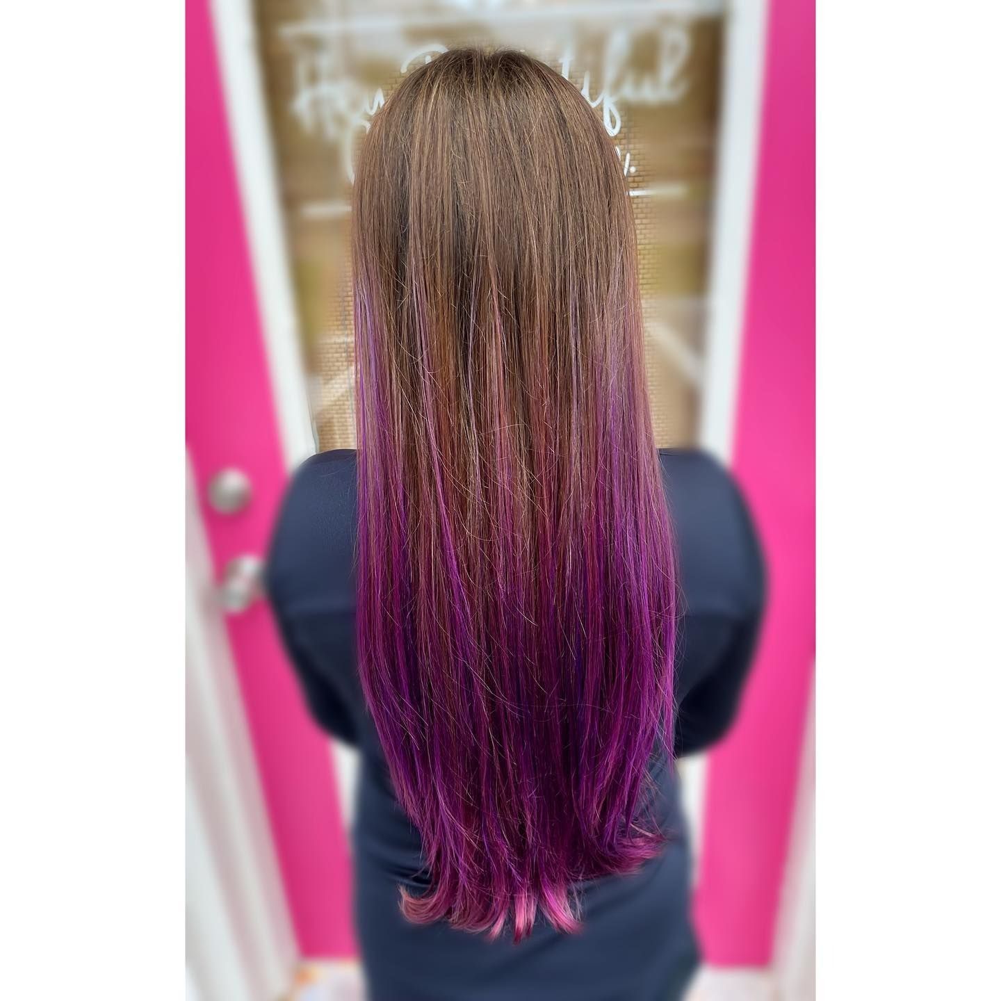 Brown hair with vibrant purple ombre, person's back to the camera, standing in front of a pink door.