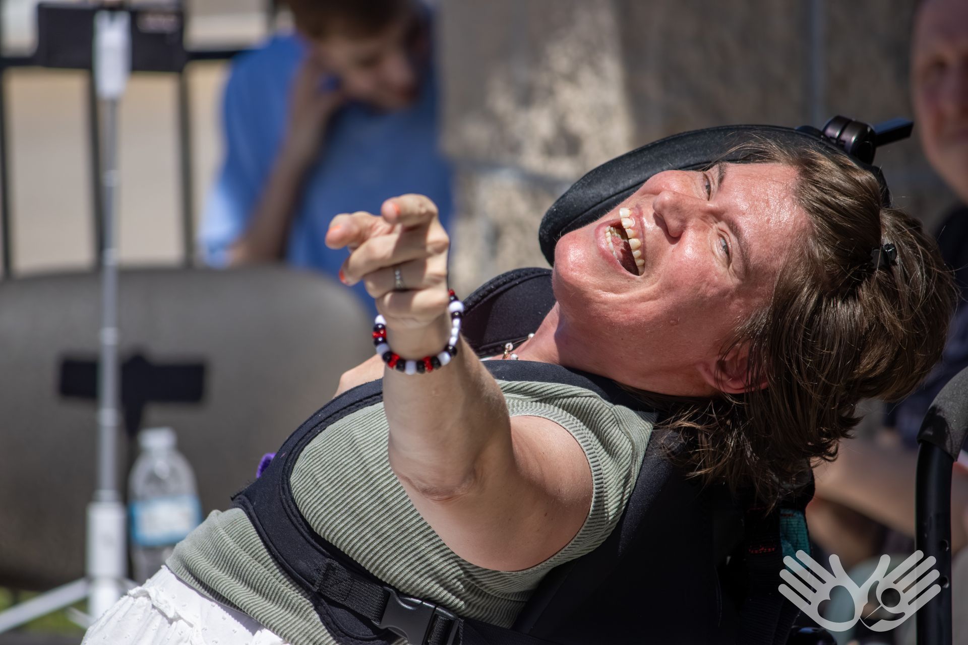 Person in a wheelchair reaching forward and smiling in a performance or therapy setting