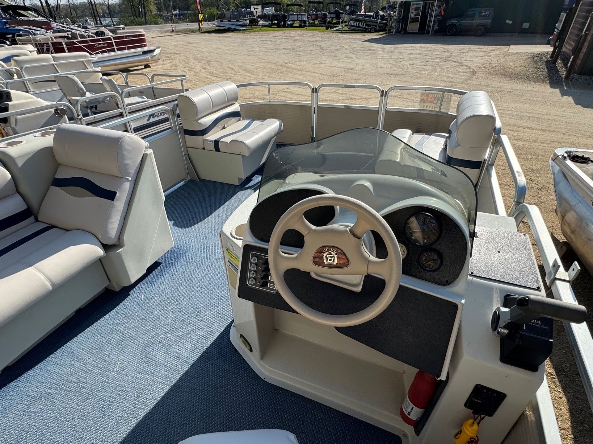 The inside of a pontoon boat with a steering wheel and seats.