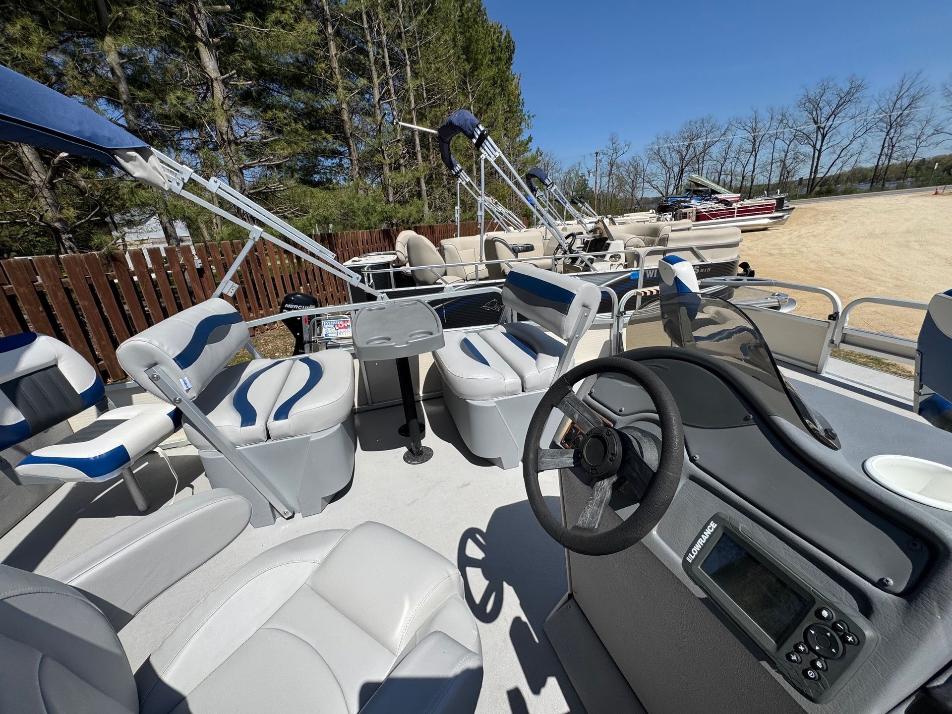 The inside of a pontoon boat with a steering wheel and seats.