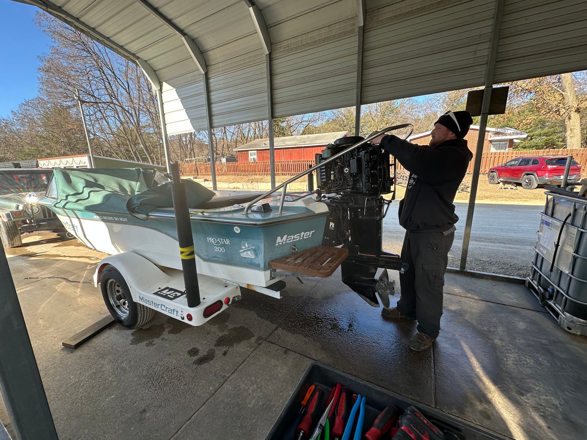A man is working on a boat engine under a canopy.