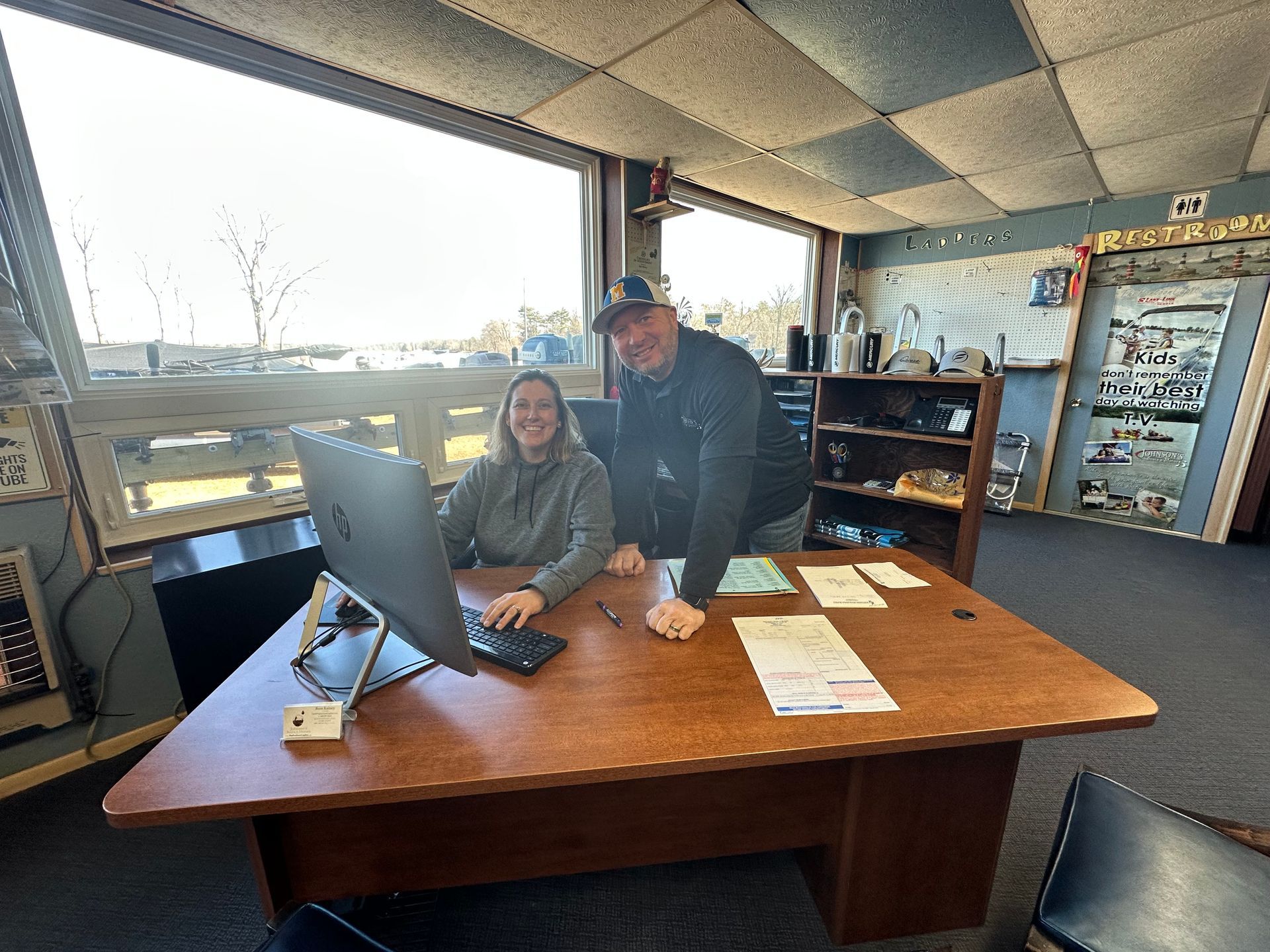 A man and a woman are sitting at a desk in front of a computer.