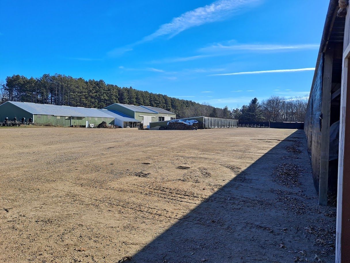 A pontoon boat is floating on top of a body of water. Kids tubing behind pontoon.