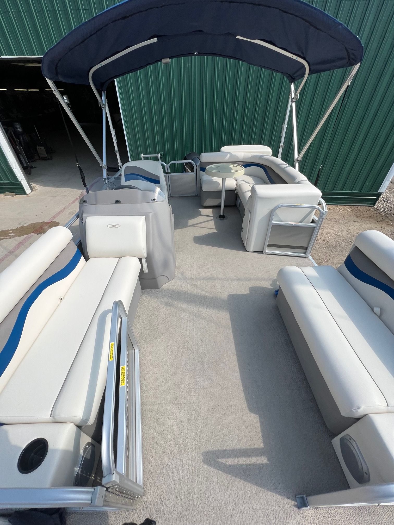 The inside of a pontoon boat with a blue canopy