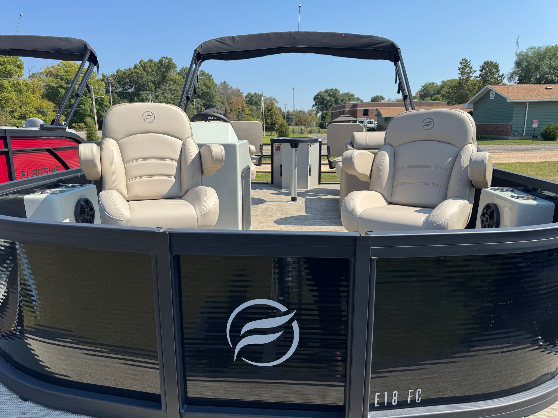 A pontoon boat with two cream-colored captain's chairs under a black canopy on a sunny day.