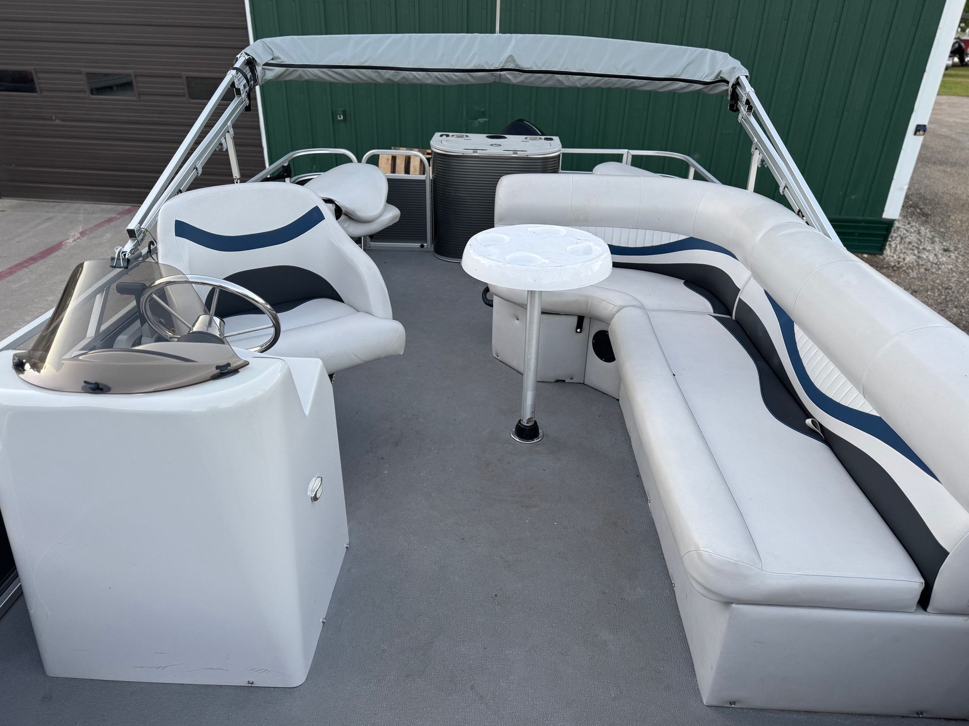 The inside of a pontoon boat with a table and chairs