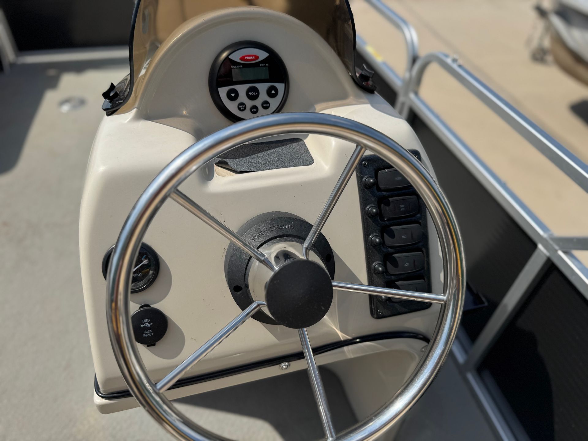 Boat helm with silver steering wheel, gauges, switches, and a digital display.