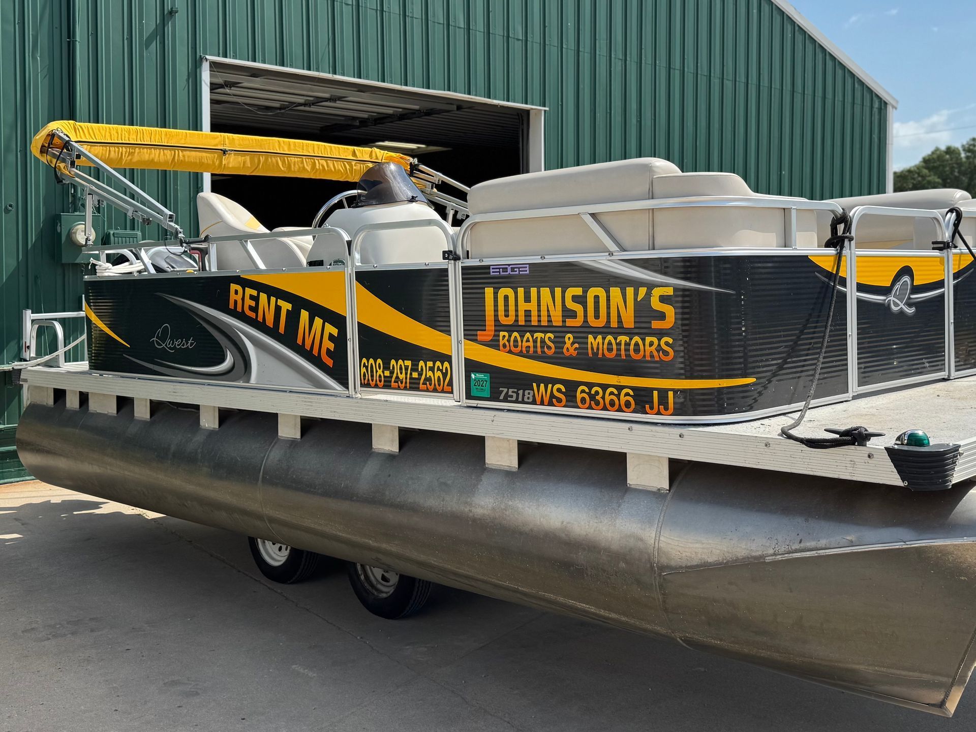 Pontoon boat in front of a green building.