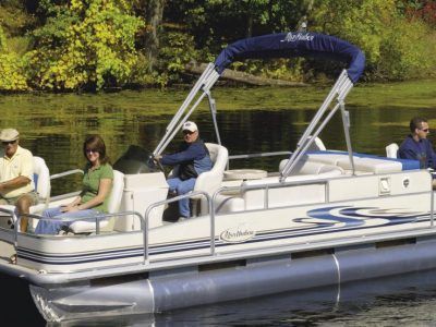 A group of people are sitting on a pontoon boat on a lake.