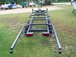 A boat trailer is sitting on top of a lush green field.