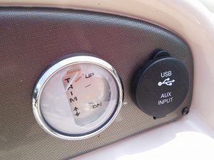 A close up of a gauge and a usb port on a boat.