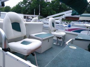 A pontoon boat with white seats and green cushions