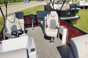 The inside of a pontoon boat with a steering wheel and chairs.