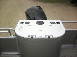 A boat with a mercury outboard motor is parked on a dirt road.